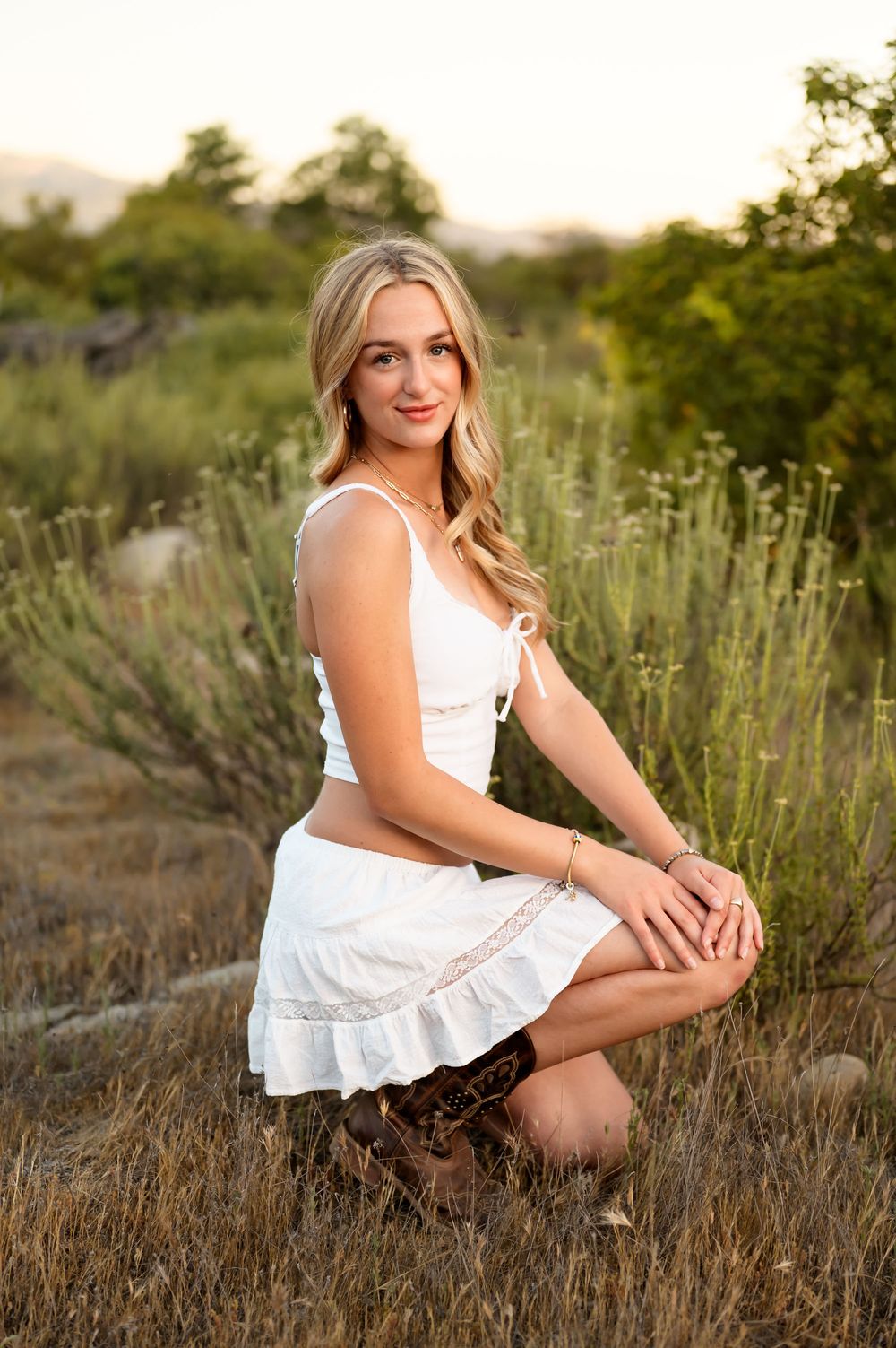 High school senior posing in white dress & cowboy boots at Ojai Valley Preserve during outdoor senior portrait session Ventura photographer