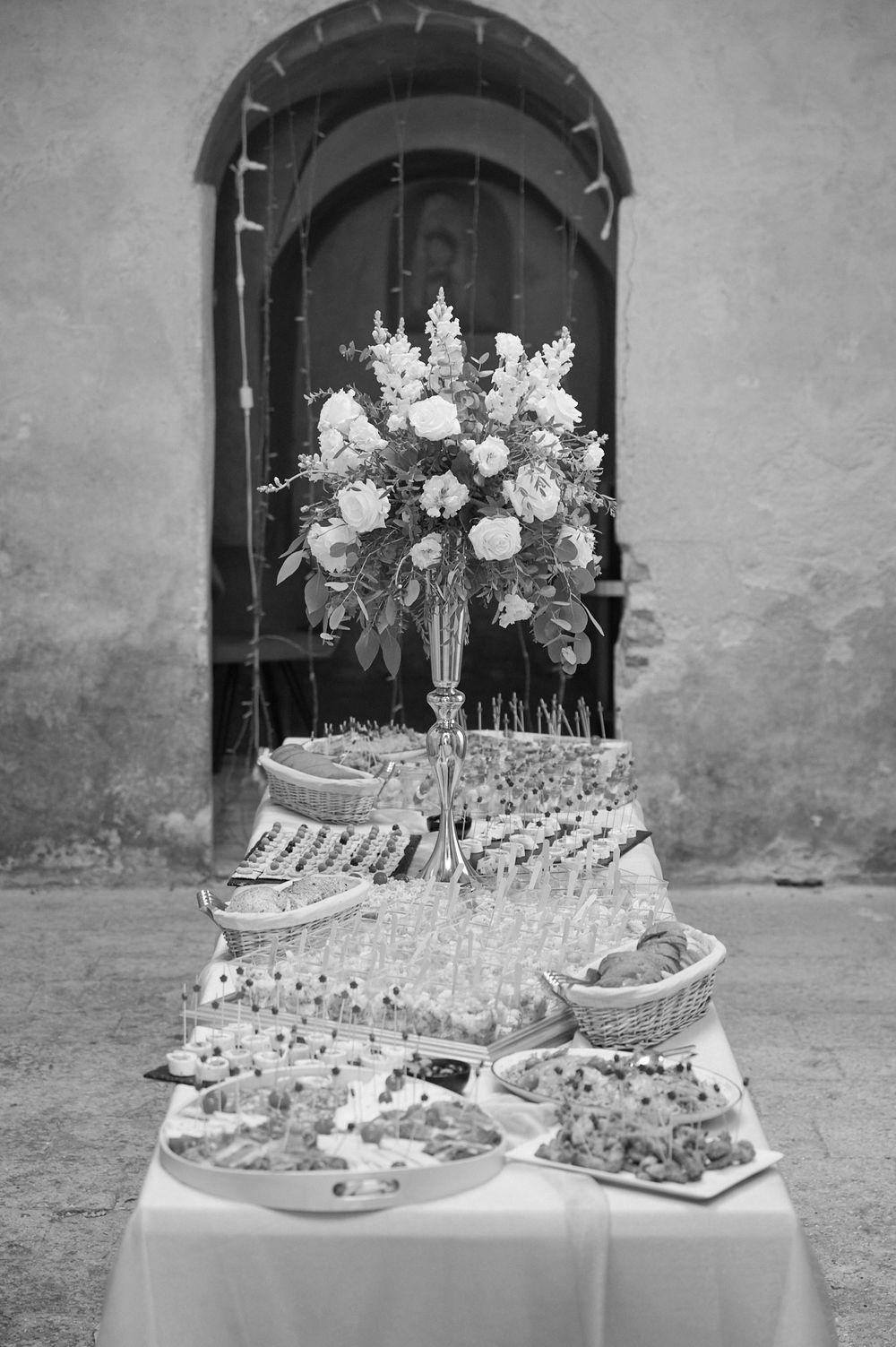 Elegant wedding dessert and appetizer table display with floral arrangements and tiered serving platters.