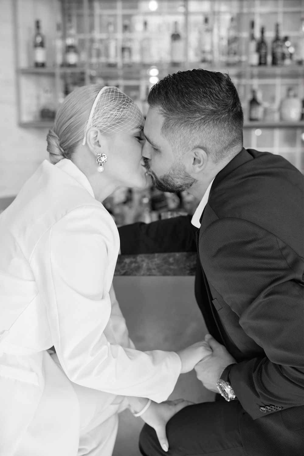 A couple in wedding attire sharing a romantic kiss at the bar.