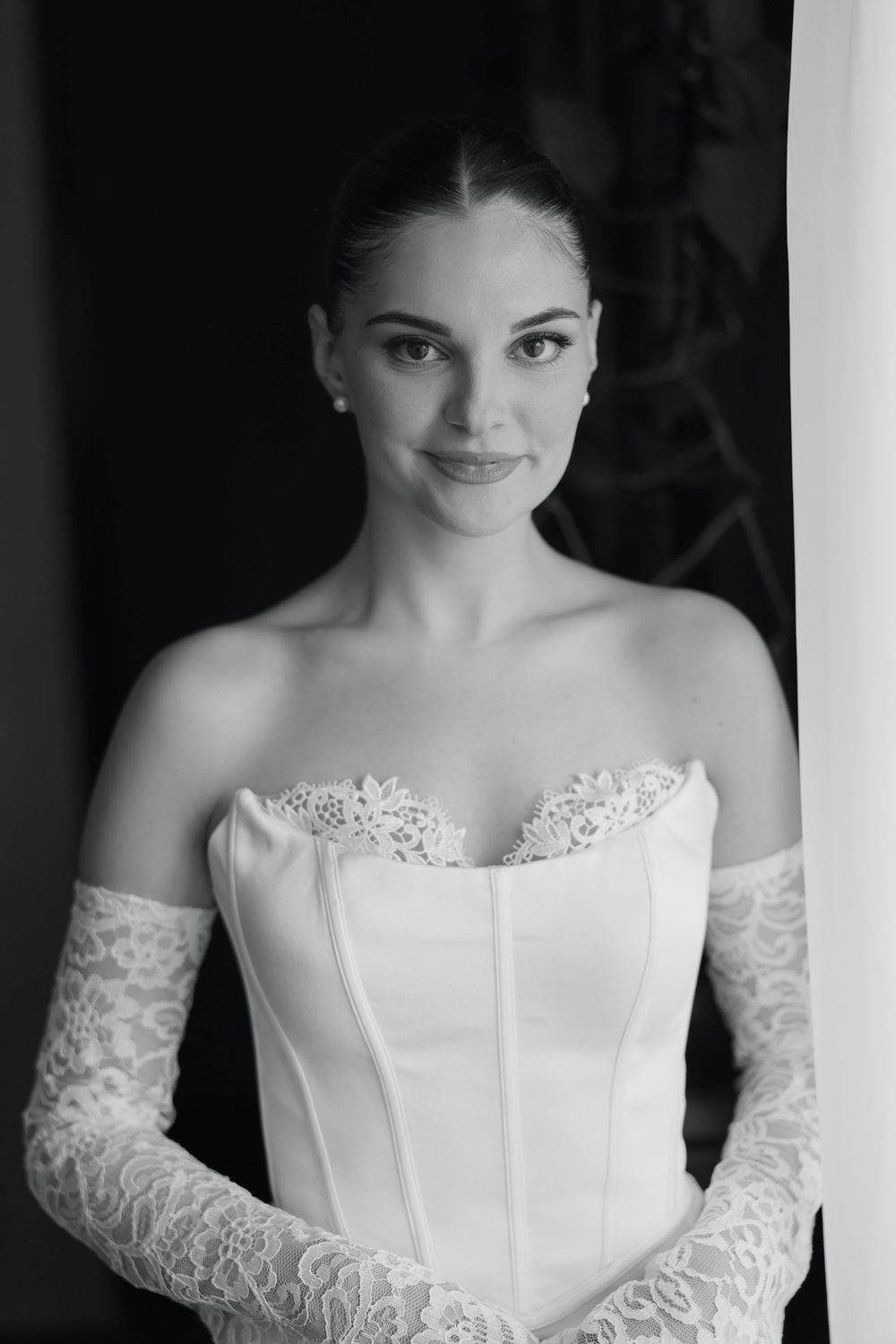 Black and white portrait series showing a bride in an elegant white strapless wedding gown with delicate lace details.