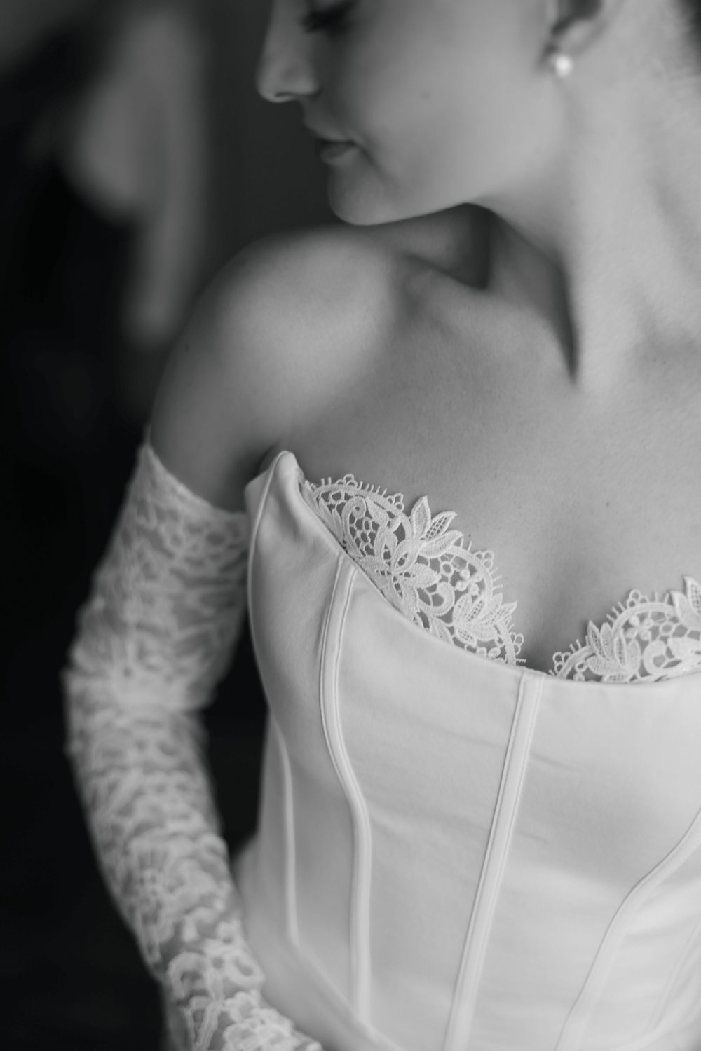 Close-up detail shots of a white lace wedding dress bodice with delicate embroidery in black and white photography.
