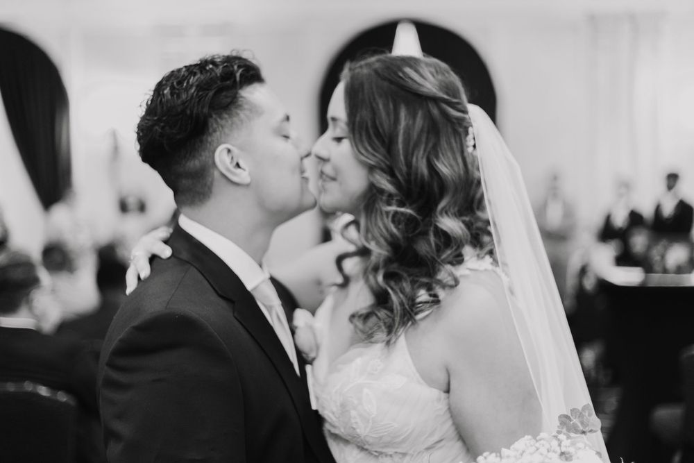 Black and white romantic wedding photo showing a tender kiss between newlyweds.