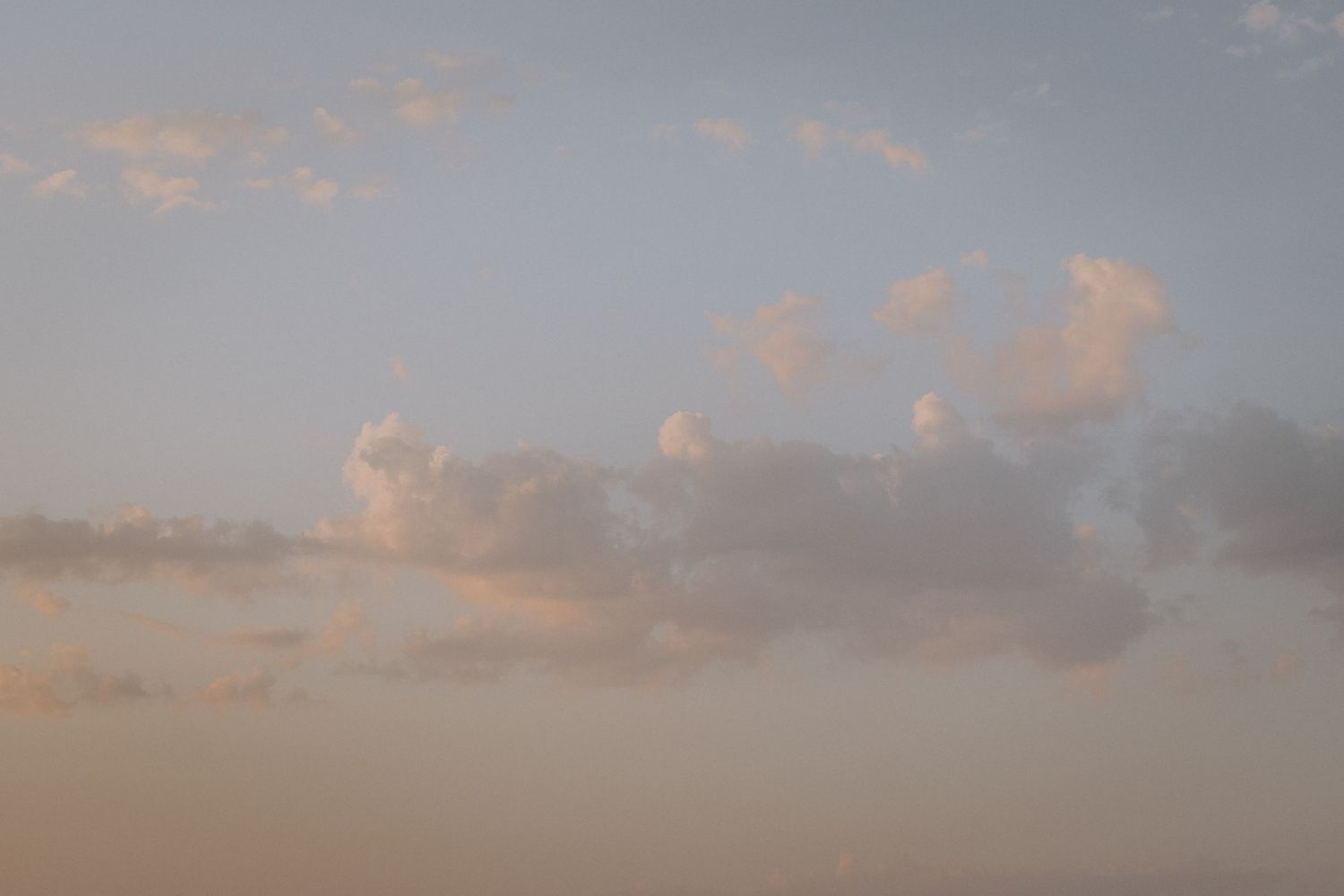 Soft pink and orange clouds float in a pastel sunset sky creating a dreamy atmosphere.