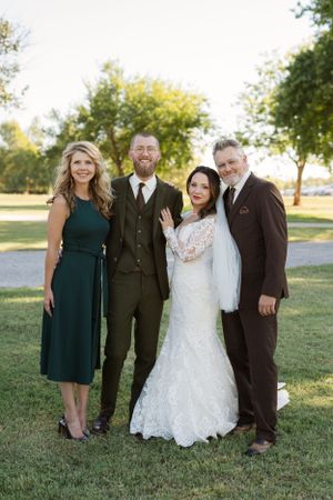Wedding party group photo with dark green dresses and white lace gown.