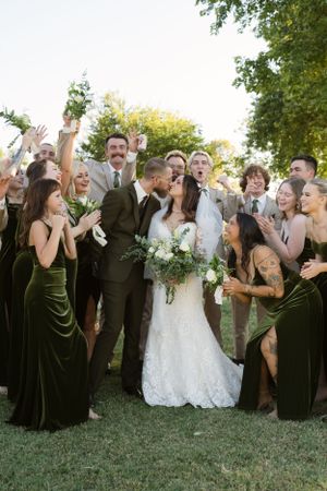 Wedding party poses for fun group photos on grass with dramatic expressions.