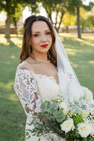 Elegant bridal portrait with lace dress and eucalyptus bouquet in natural lighting.