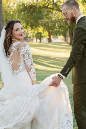 A beautiful lace wedding dress flows in the golden sunlight during an outdoor photo session.
