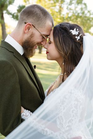Romantic wedding couple shares an intimate moment in a sunlit garden setting.