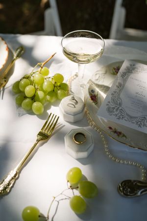 Elegant place setting with green grapes, gold cutlery and white linens in natural light.