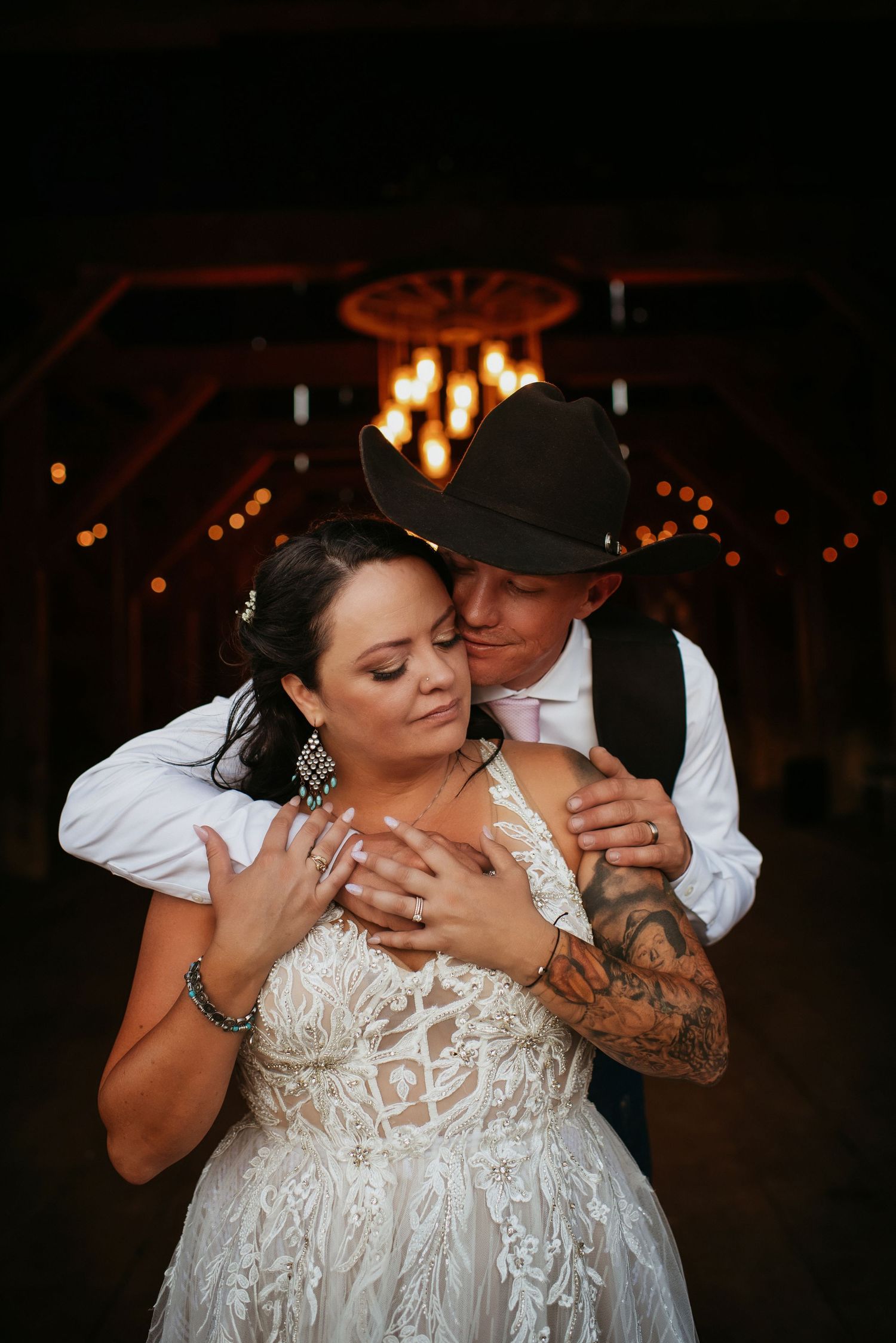 Lake Tahoe wedding photographer captures intimate rustic wedding photography – bride in lace gown and groom in cowboy hat embrace.