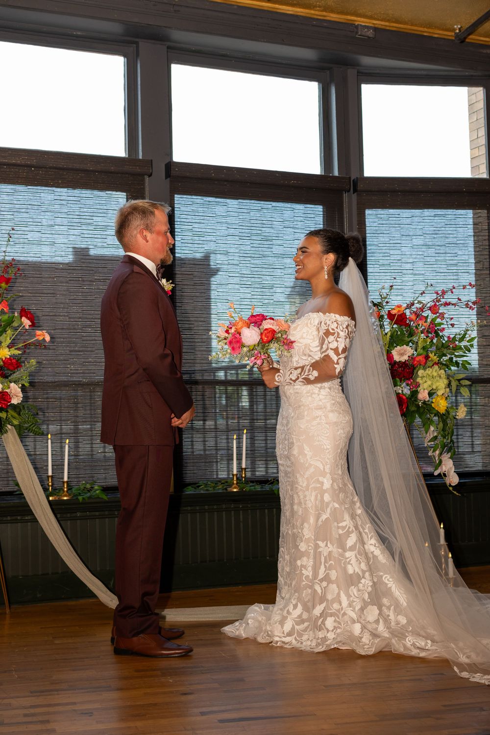 A bride and groom exchange vows at a waterfront wedding ceremony with floral arrangements and candlelit decor.