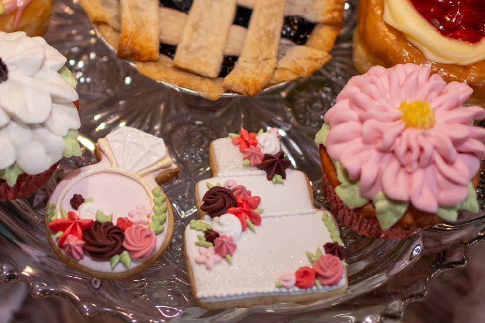Sweet decorated cookies with floral designs and cherries arranged on a glass plate.