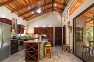 Modern gourmet kitchen with center island, stainless steel appliances, and wood cabinets in a gated community in Atenas