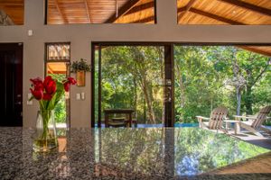 Elegant dining room with wooden table and matching chairs, overlooking the garden in a gated community in Atenas