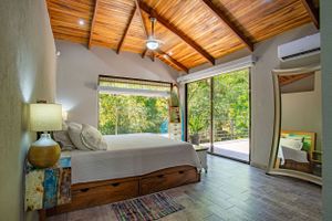 Master bedroom with king-size bed, wooden furniture, and private balcony in a gated community in Atenas. A haven of tranquility