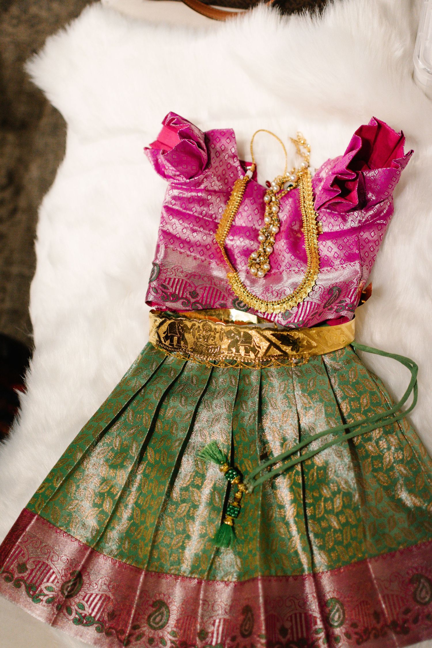 Overhead photo showing Annaprashana ceremony clothing setup with jewlery and ritual items.