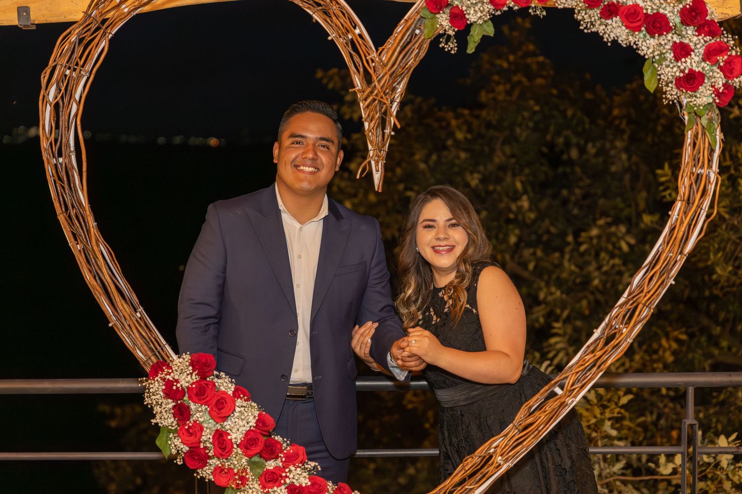 Heart-shaped arch decorated with red flowers and lights for wedding photography.