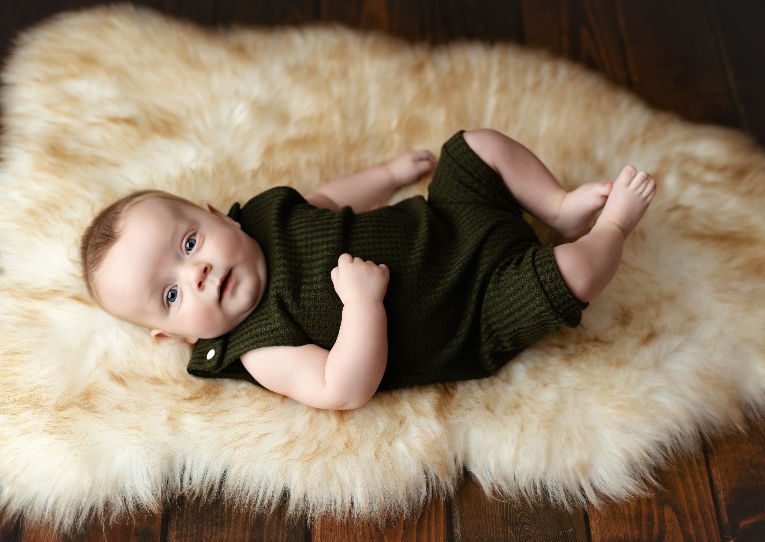 A 6-month-old with a green outfit laying on his back. Greenville SC newborn photographer, Easley SC newborn photographer