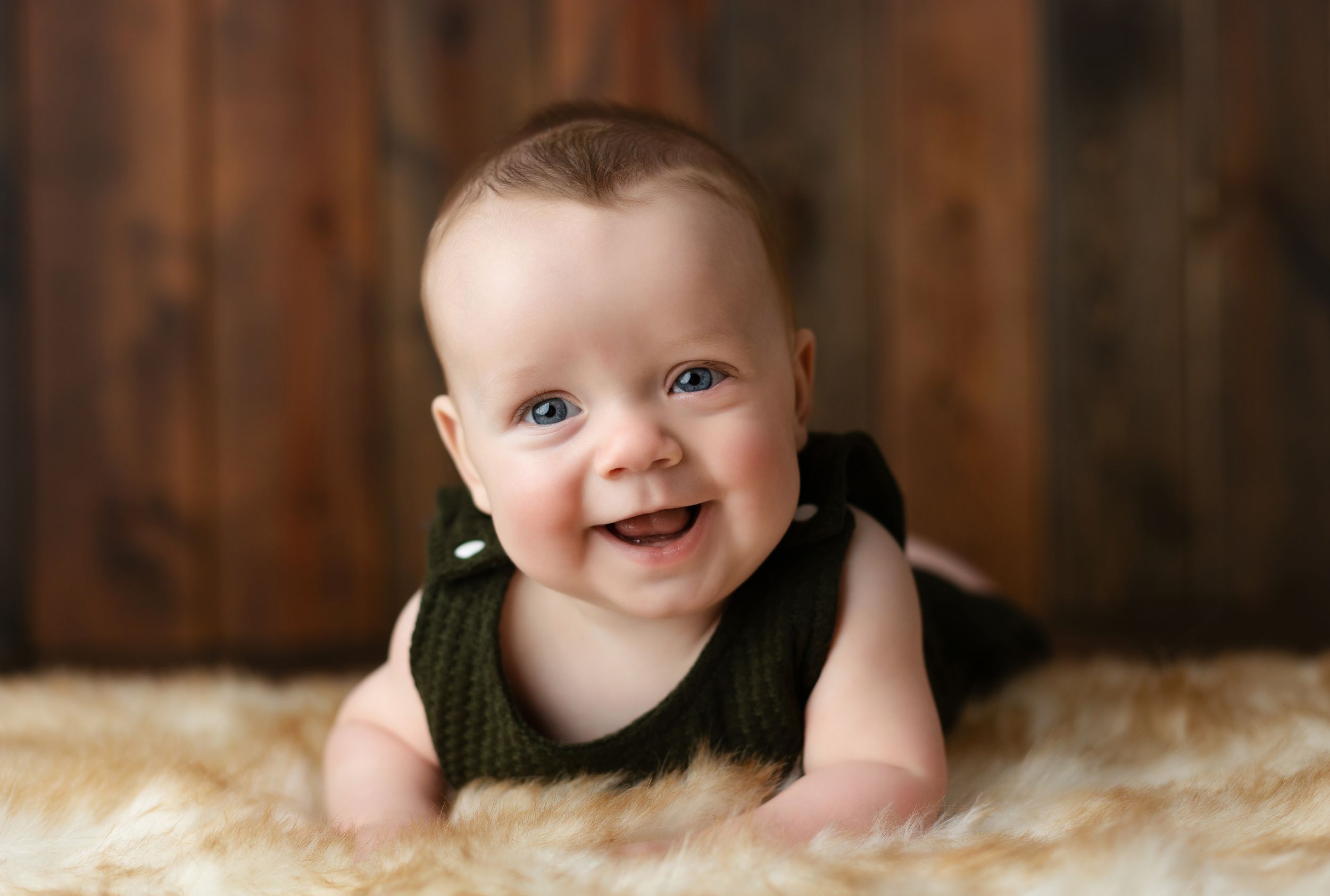 A 6-month-old with a green outfit laying on his belly. Greenville SC newborn photographer, Easley SC newborn photographer