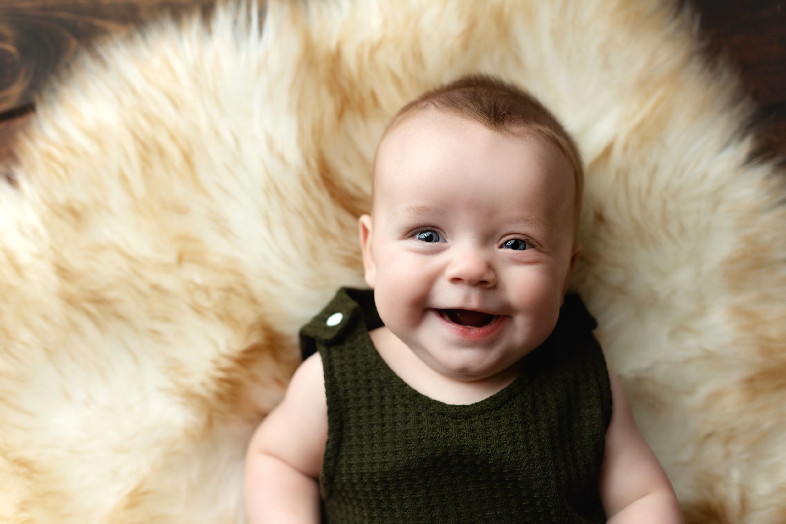 A 6-month-old with a green outfit laying on his back. Greenville SC newborn photographer, Easley SC newborn photographer