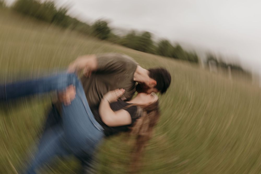 A playful spinning motion shot of a couple dancing in a field creating a blurred effect.
