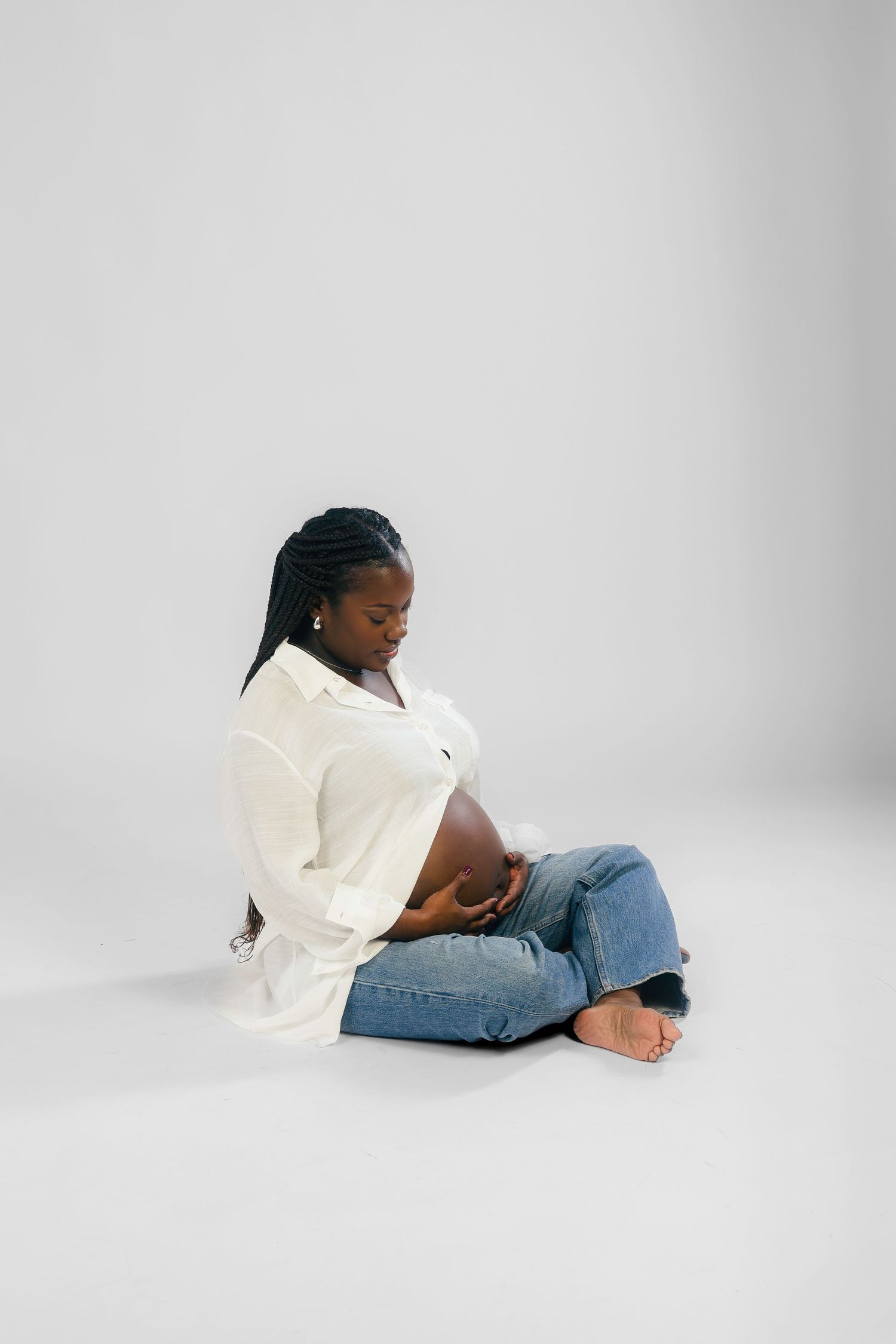 Person in white shirt and jeans lying on floor against grey background in artistic pose sequence.