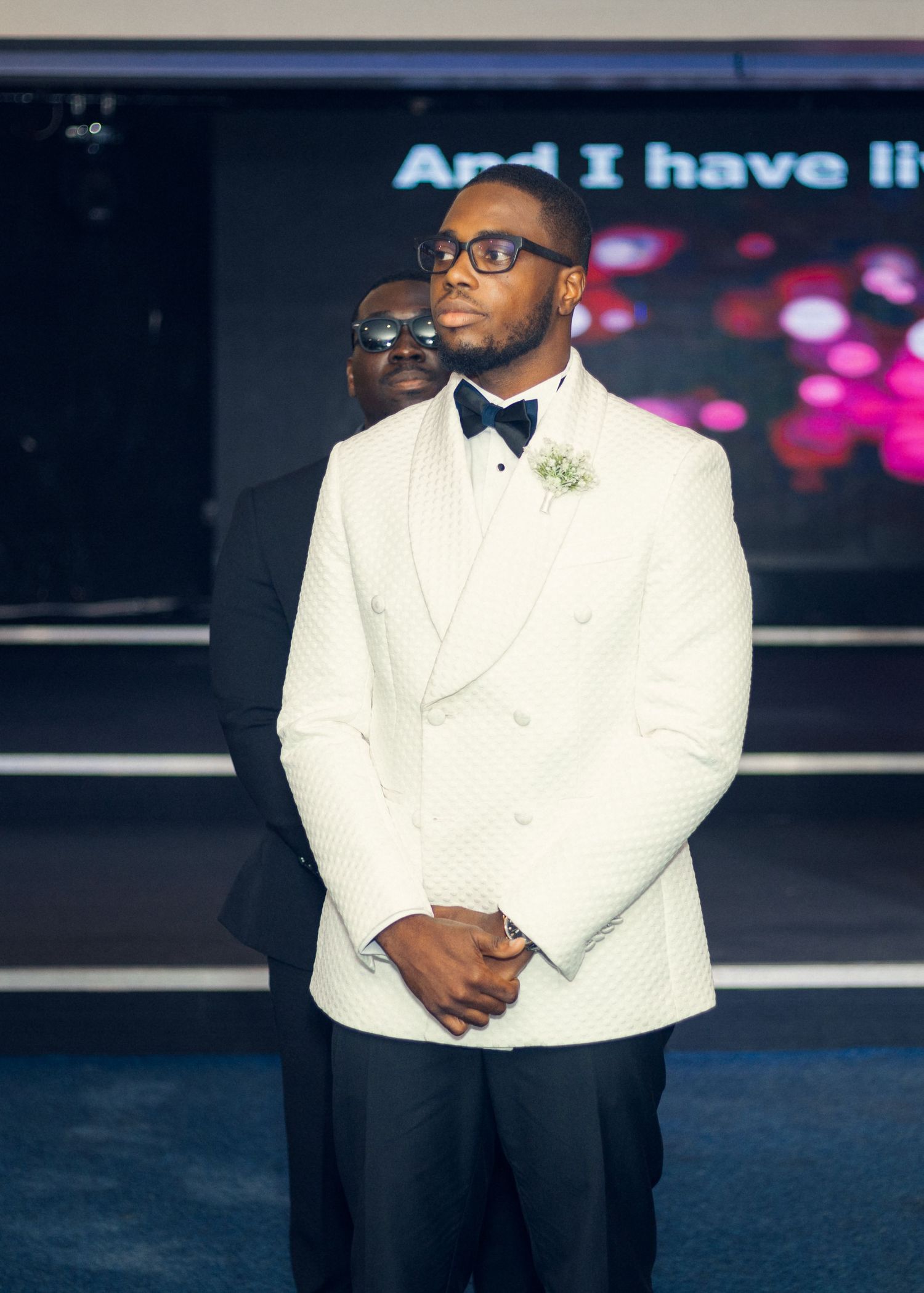 A groom in a white tuxedo jacket stands at the altar during the ceremony.