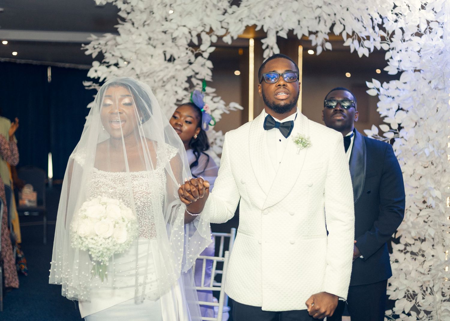 A wedding couple stands at the altar as white confetti falls during their ceremony.