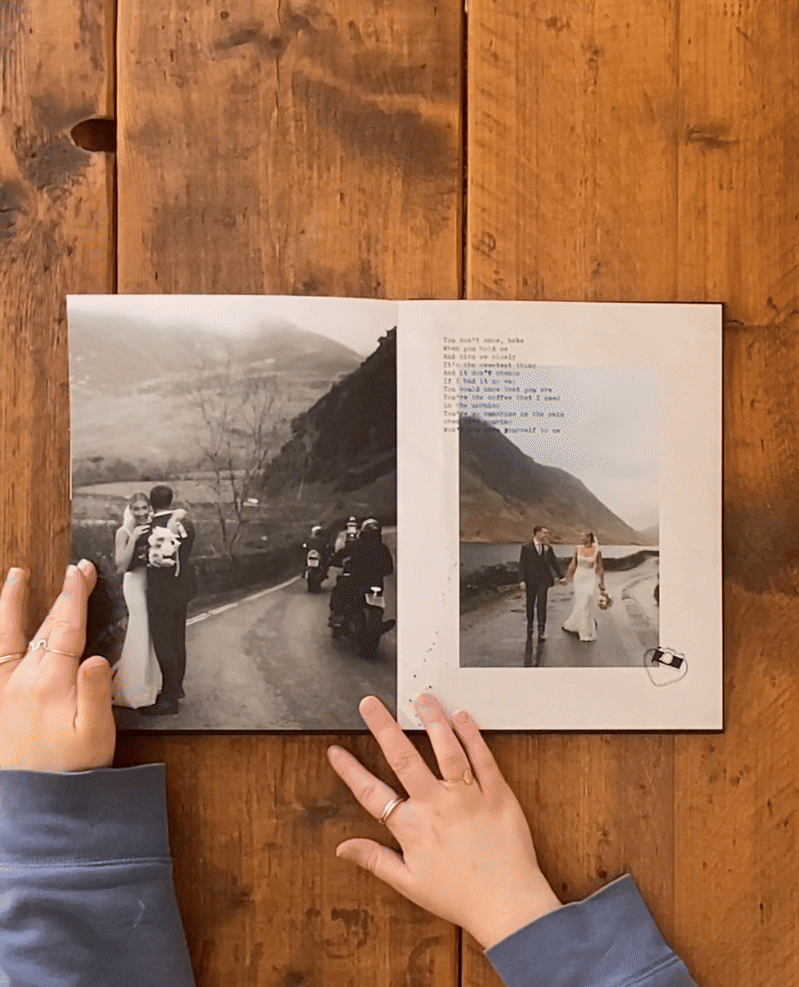 Hands turning pages of a photo album showing black and white mountain landscape photographs on wooden background.