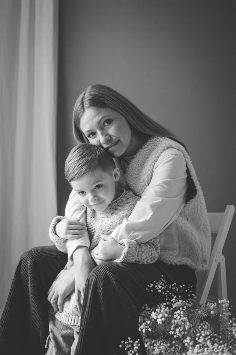 Black and white photo series showing tender moments between parent and child sitting together in soft window light.