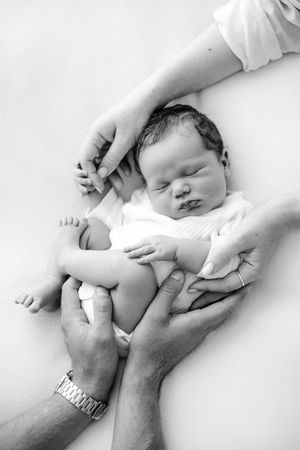 A series of black and white photos showing gentle hands massaging and soothing a small baby.