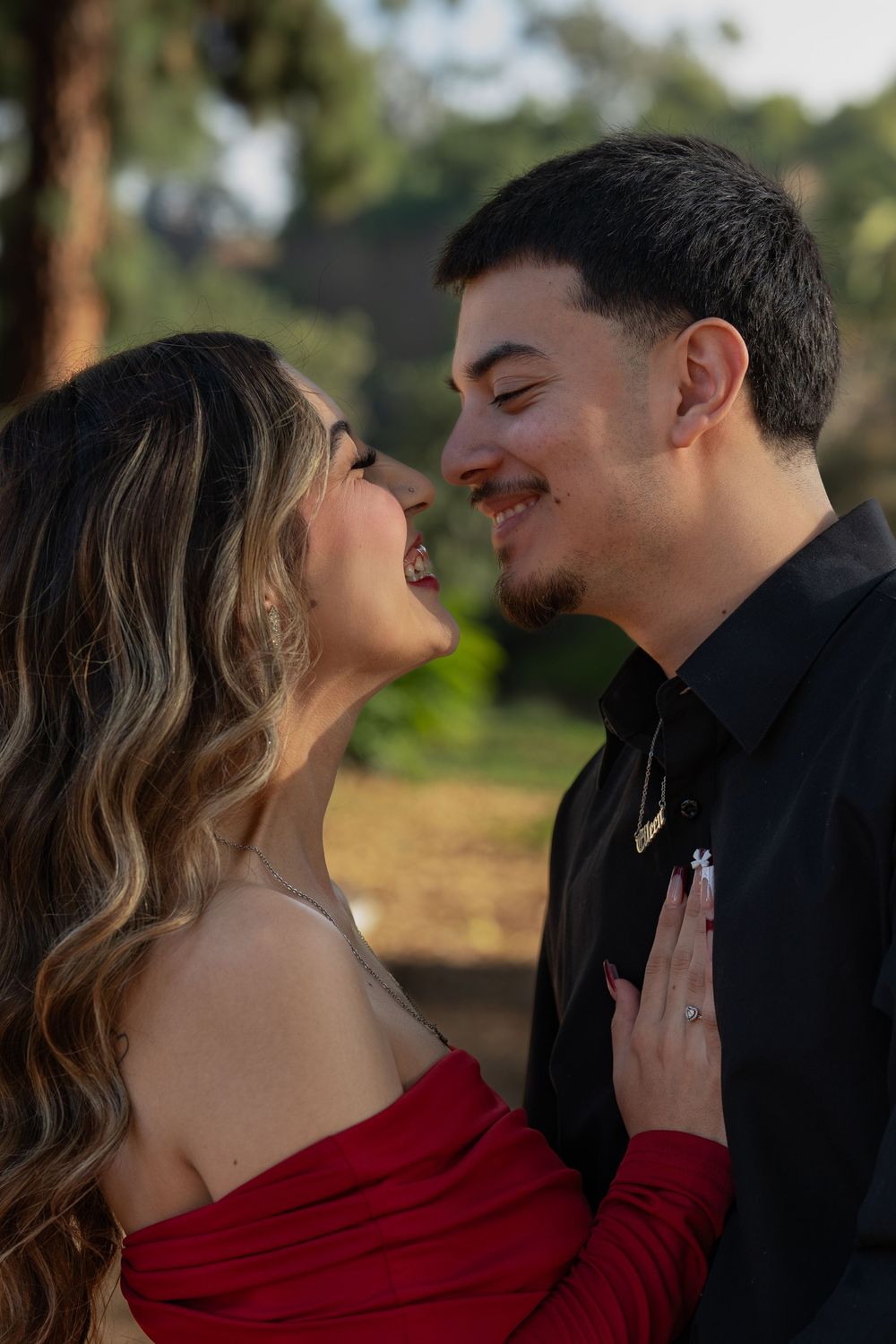 A romantic couple in a red dress and black attire share intimate moments in a series of outdoor portraits at sunset.