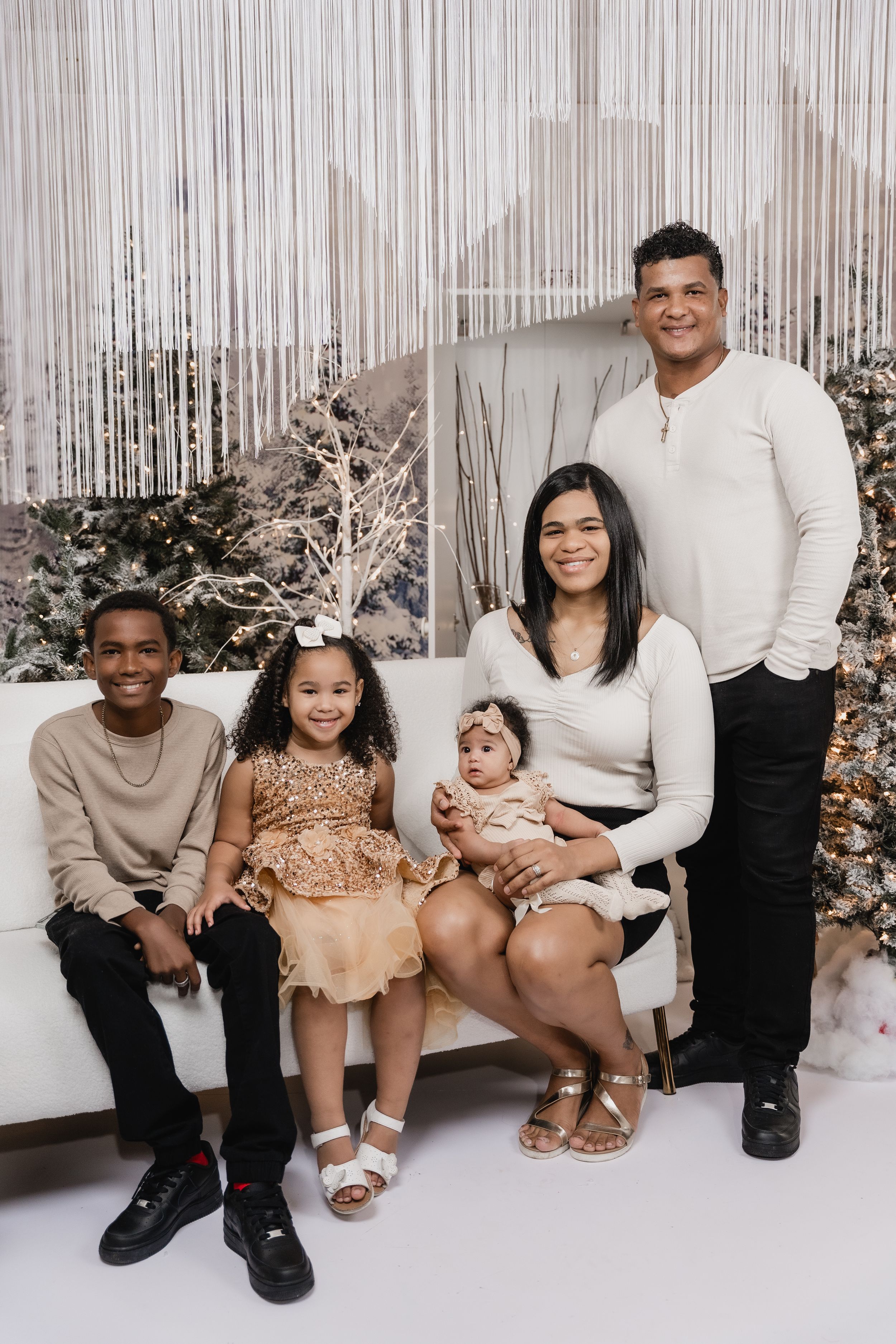 A festive family portrait session with winter decorations and silver tinsel backdrop.