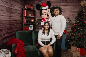 A festive holiday photo featuring Mickey Mouse and a decorated Christmas backdrop.