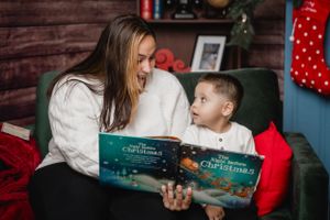 A heartwarming moment of reading a Christmas storybook together in a festively decorated room.