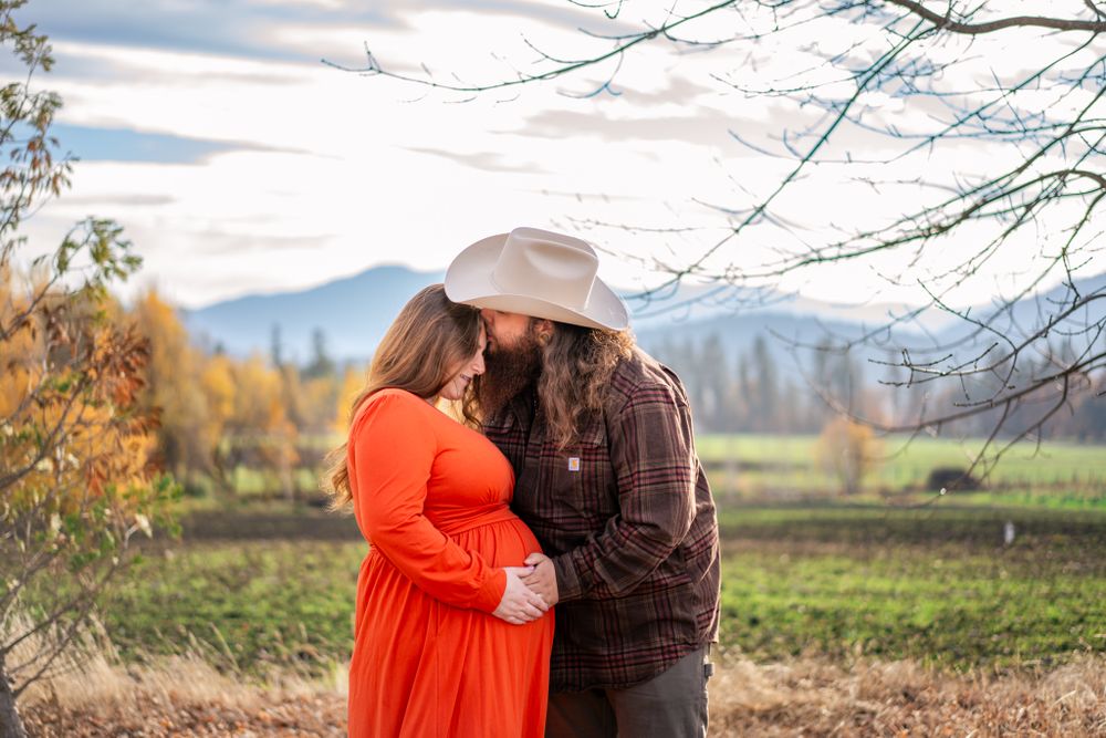dad kisses mom while she looks at baby in her belly