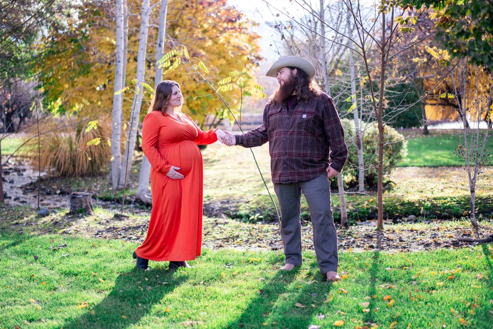 portrait of mom and dad by trees and a small creek before their first baby