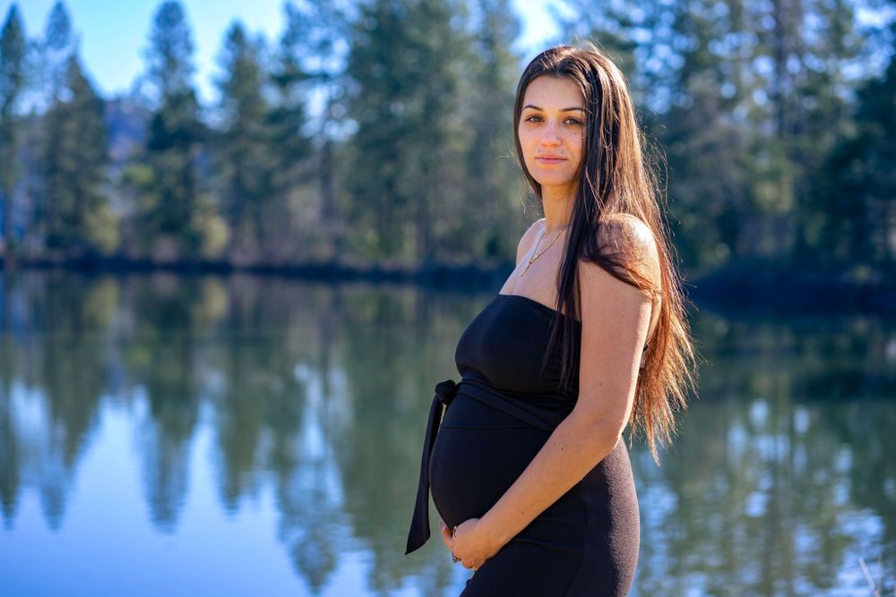 maternity portrait in black with a pond in the background