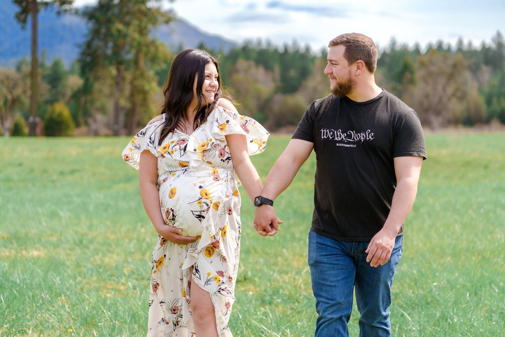 maternity portrait of mom and dad sharing a moment while walking in a field