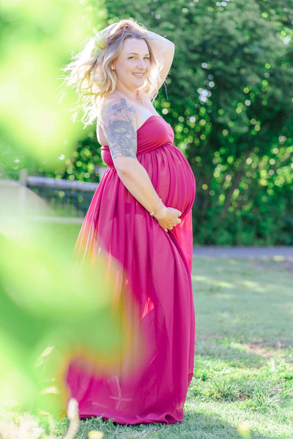 maternity portrait outdoors with greenery and a pink dress