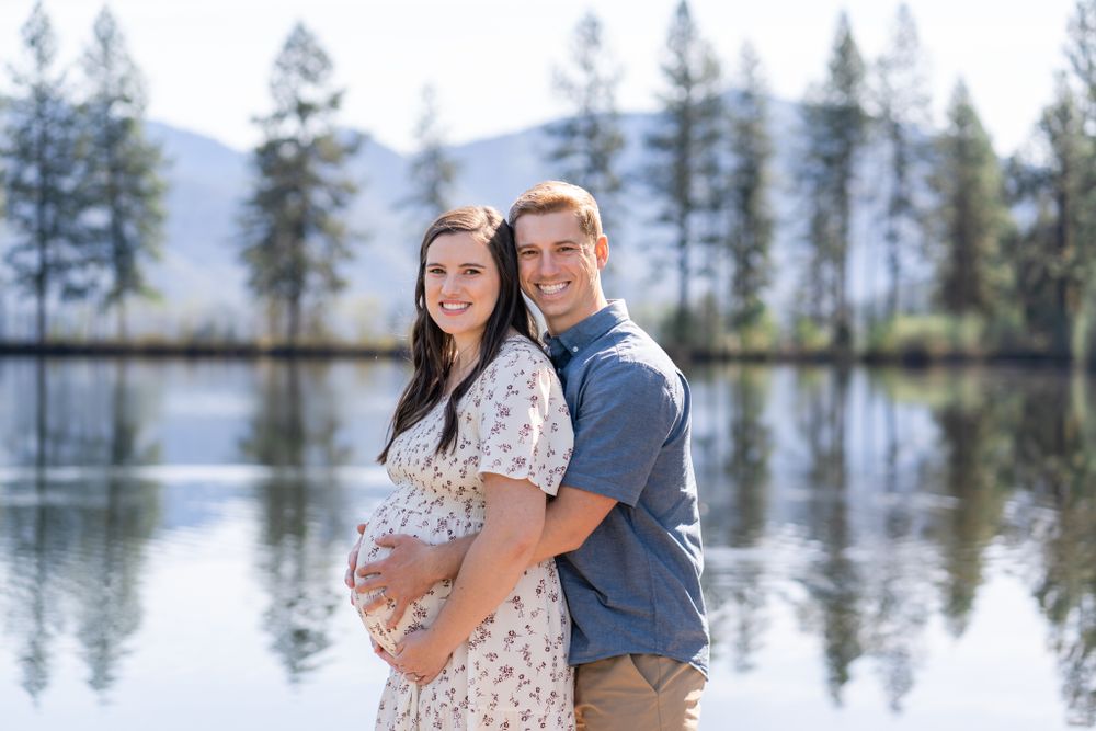 portrait of mom and dad with the pond behind them before their first child is born