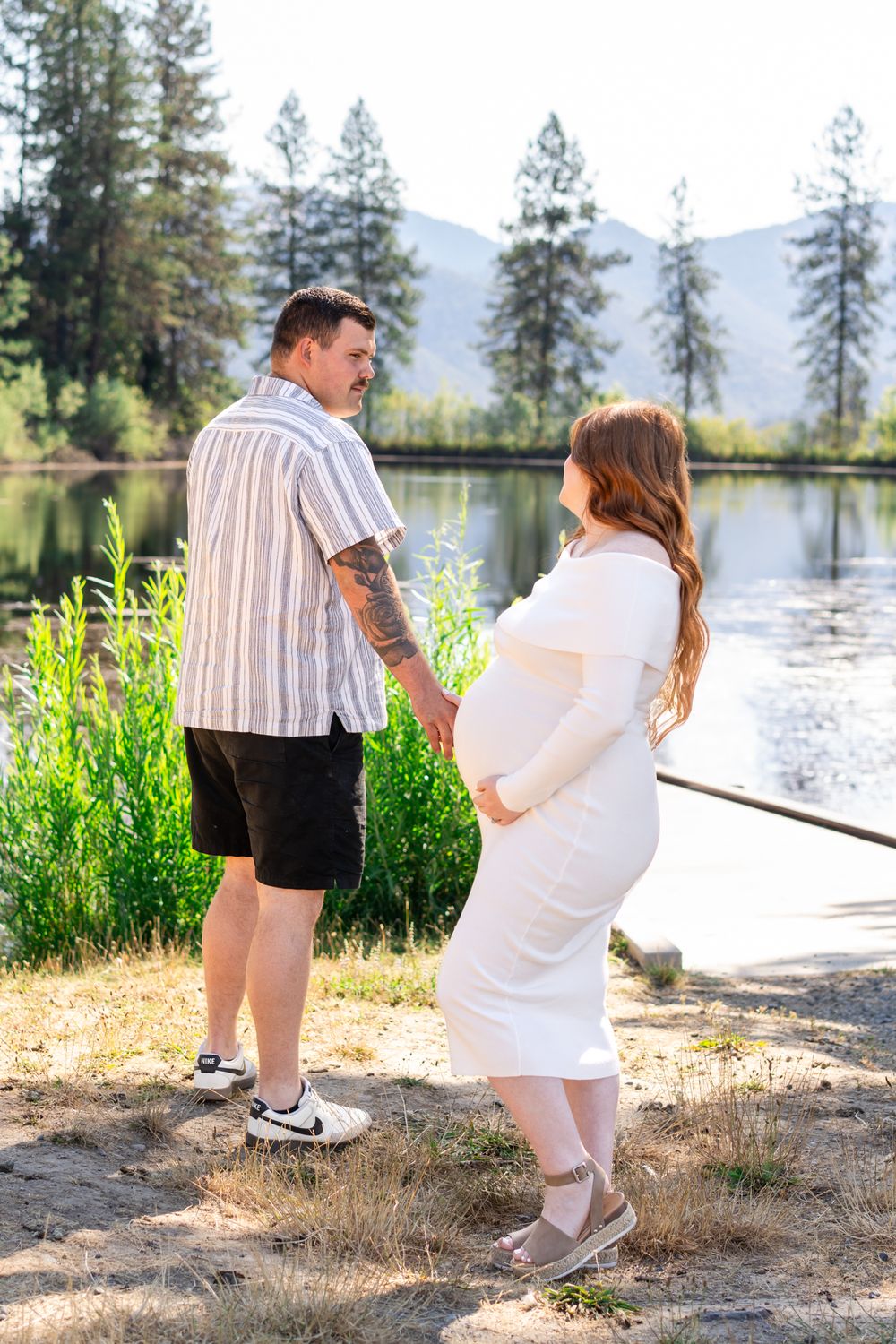 Maternity portrait of dad looking back at mom by a pond at Pacifica in Southern Oregon