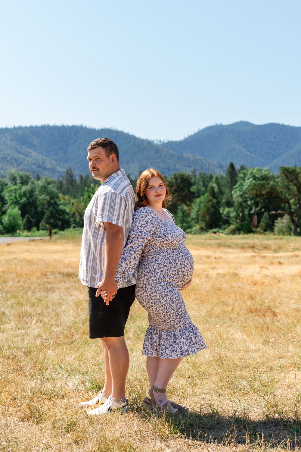 Maternity portrait with mom and dad back to back with blue mountains in the background