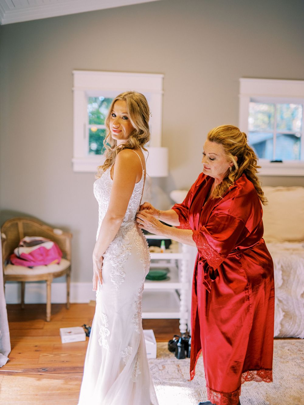 A wedding dress being fitted and adjusted in a sunlit dressing room.