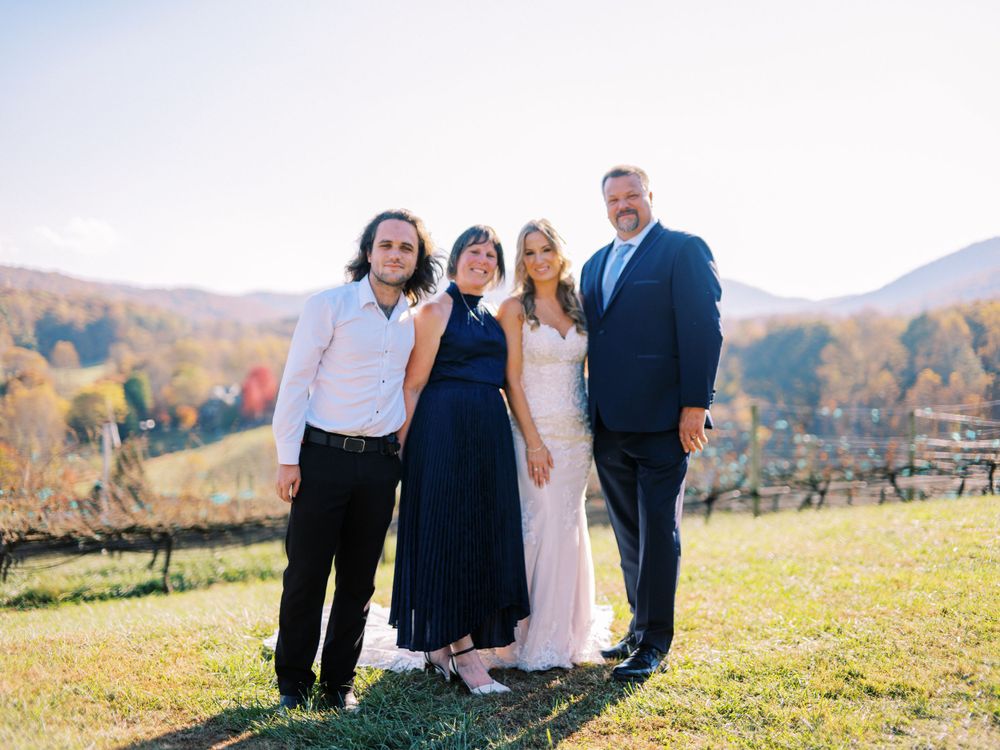 Wedding party poses together on a hillside during autumn with mountains in the background.