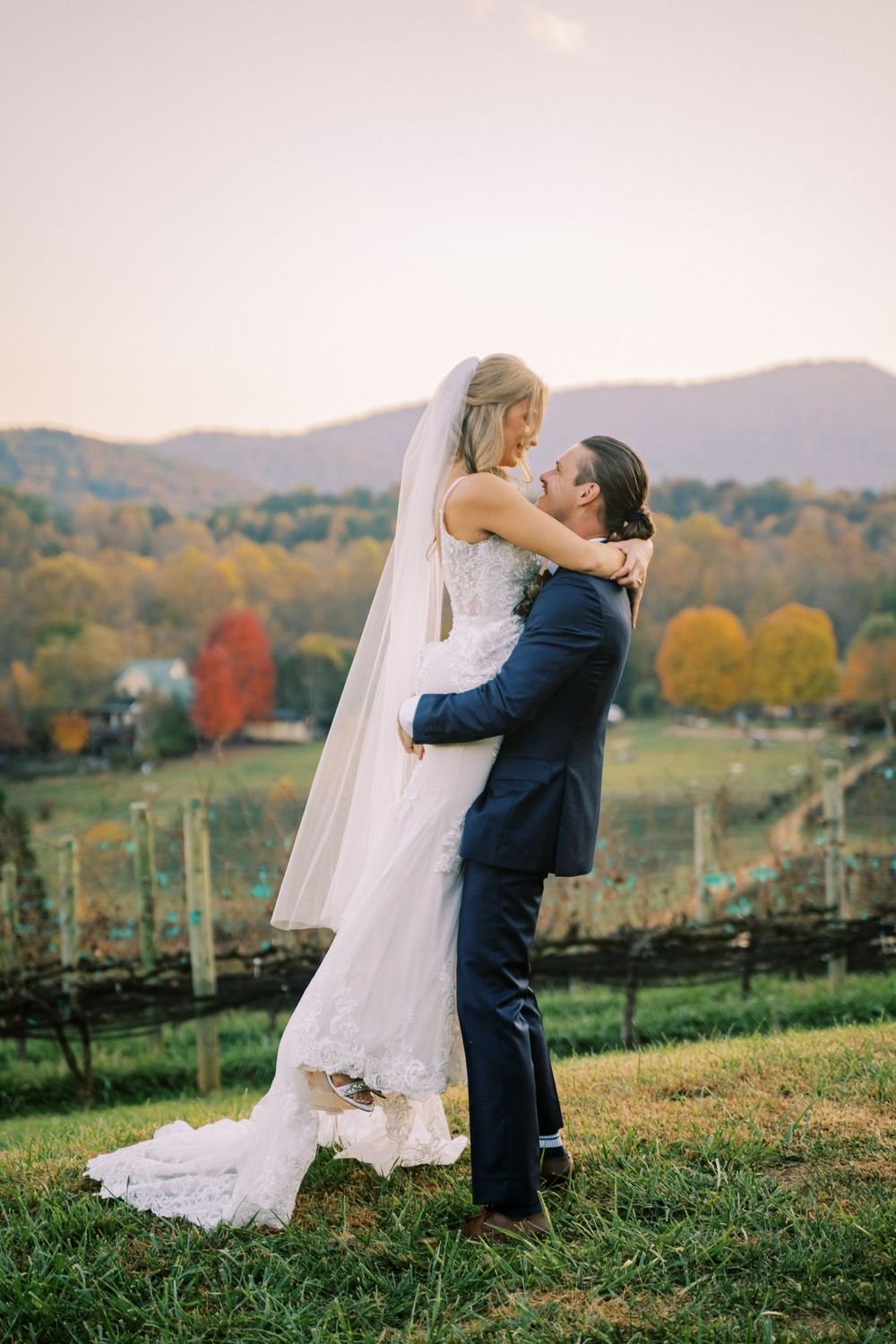 Romantic moment between newlyweds on a hilltop with mountain views and vineyard backdrop.