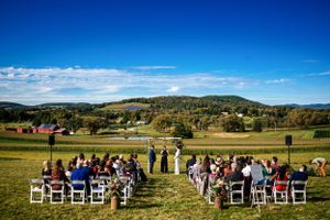 Wide aerial view of an outdoor wedding ceremony set against a stunning rural Vermont landscape.
