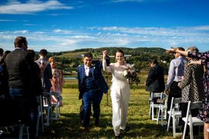 Newlyweds celebrate joyfully as they walk back up the aisle after their outdoor farm wedding ceremony.