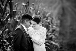 Black and white close-up of bride and groom sharing an intimate moment by cornfield.