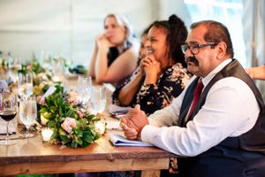 Wedding guests laugh and smile while seated at a decorated reception dinner table.